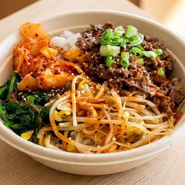 A close-up of a bibimbap bowl with bulgogi, kimchi, spinach, and bean sprouts.